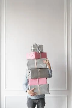 A man holds an ornate stack of packed holiday boxes, gray and pink color. Gif 写真素材