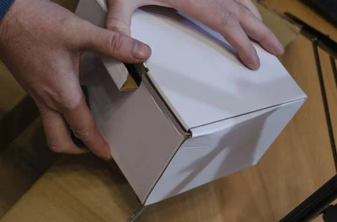 Man holds parcel in white rectangular cardboard box. 库存照片