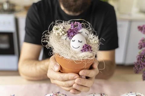 Man holds a pot of Easter eggs with spring flowers. Eggs with sleeping merry Stock Photos