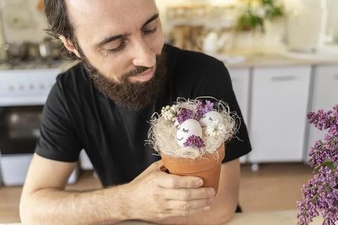 Man holds a pot of Easter eggs with spring flowers. Eggs with sleeping merry Stock Photos
