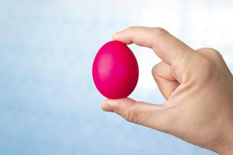 Man holds red Easter egg in hand, close up isolated on white background Stock Photos