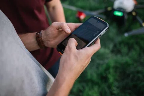 Man holds remote controller with his hands while copter is flying on backgr.. Stock Photos