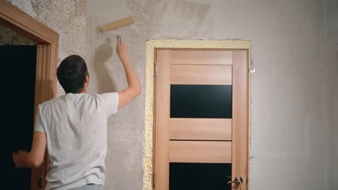 A man holds a roller in his hands and covers the putty wall with glue Vidéo 145791765