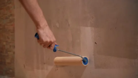 A man holds a roller in his hands and covers the putty wall with glue Vidéo 146040944