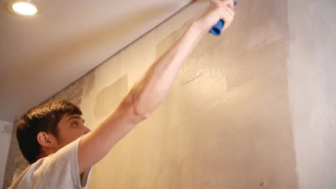 A man holds a roller in his hands and covers the putty wall with glue Vidéo 146041841