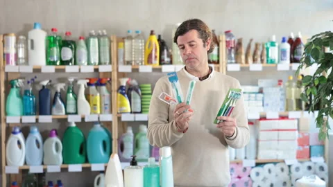Man holds a set of toothbrushes in his hands, standing against the background of Stock Footage 310530301