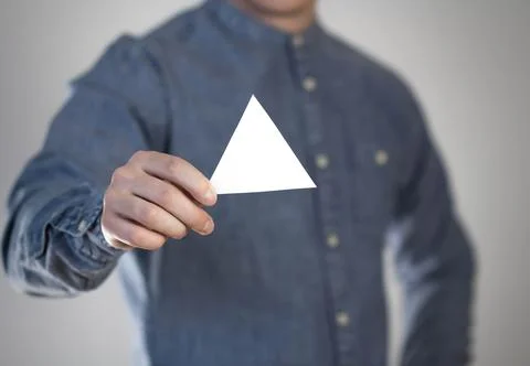 A man holds a small white triangular piece of paper. A flyer in the hands of  Stock Photos