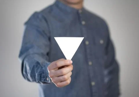 A man holds a small white triangular piece of paper. A flyer in the hands of  Foto stock