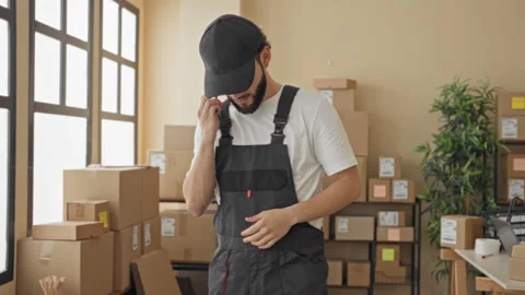 Man holds smartphone to ear amid stacked parcels and packing boxes in a bui.. Stock Footage 337371953