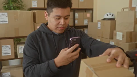 Man holds smartphone, taps screen and reaches for parcel in building while .. Video stock 337353907
