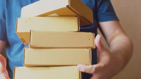 A man holds a stack of cardboard boxes in his hands 스톡 동영상 273512050