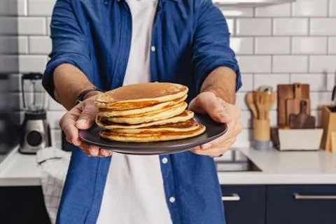Man holds a stack of fresh baked pancakes Stock Photos
