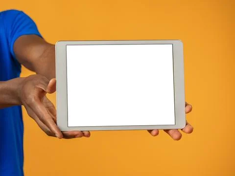 Man holds a tablet with white screen in front of orange background during Stock Photos