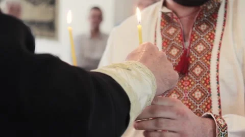 Man holds two candles in a temple in a traditional Ukrainian dress at christenin Stock Footage 201431195