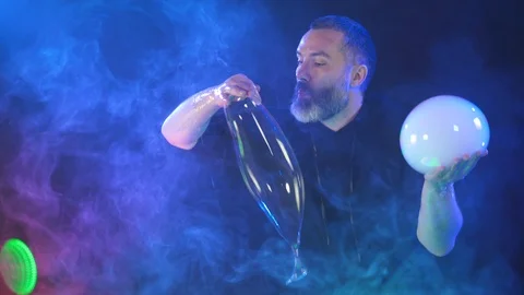 A man holds two soap bubbles in his hands and connects them Stock Footage 125691223