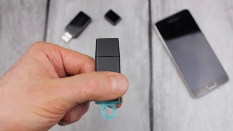 A man holds a USB disk against the background of a flash drive and a phone. Stock Footage 194672351