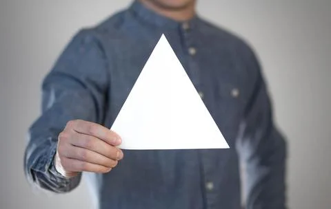 A man holds a white triangular piece of paper. A flyer in the hands of a man. Stock Photos