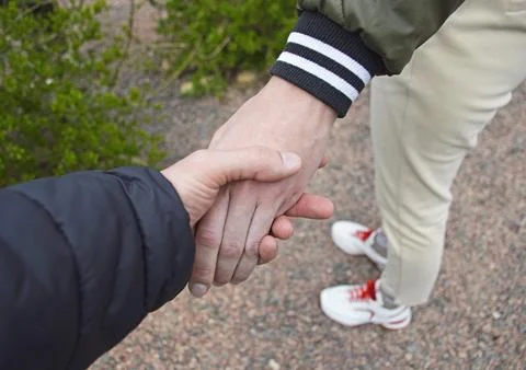 A man holds a woman's hand while walking outdoors Stock-Fotos