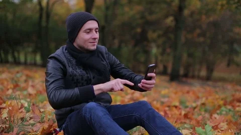 Man holiding smartphone and start having a videocall while sitting in the park Video stock 71252602