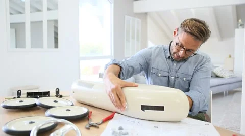 Man at home assembling toy car parts Stock Footage 56065667