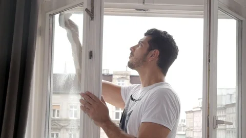 A Man at Home Cleaning a Window Stock Footage 93943895