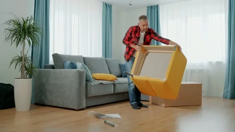 A man in home clothes assembles a soft chair himself. Stock-Footage 165839265