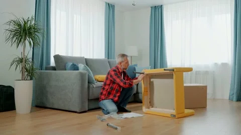 A man in home clothes assembles a soft chair himself. Video stock 171103288