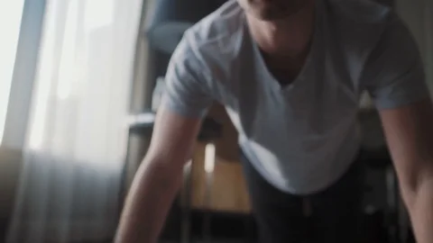 A man in home clothes is pressed off the floor. He does sports at home. Stock Footage 122817491