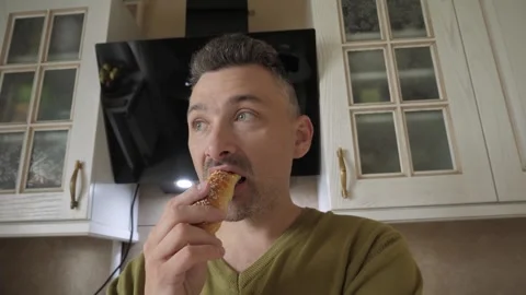 Man in home kitchen bites golden pastry Stock Footage 341832862