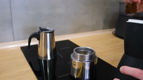 A man at home in the kitchen pours coffee into a geyser coffee maker Stock Footage 168572349