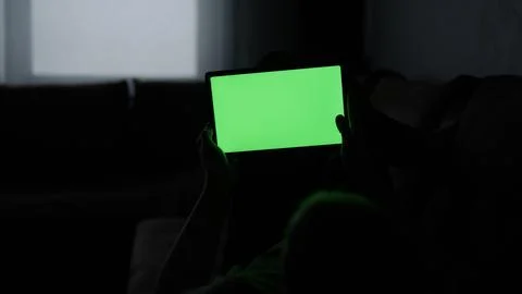 Man at home lying on a couch with tablet pc with green screen Stock Photos