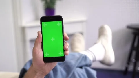 Man at Home Lying on a Couch using Smartphone with Green Mock-up Screen, Doing Stock Footage 130652292