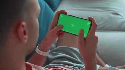 Man at Home Lying on a Couch using Smartphone, Holds it Horizontally in Stock Footage 241745915