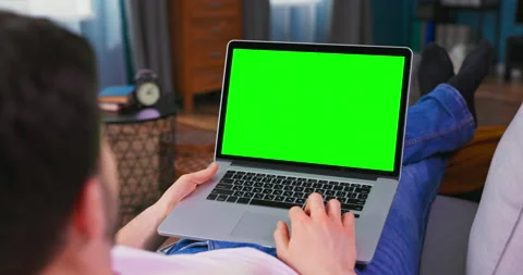 Man at Home Lying on a Couch Working on Laptop Computer with Green Mock-up Vídeo Stock 154857651