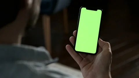 Man at home lying on a sofa and using smartphone with green mock-up screen Stock Footage 144682726