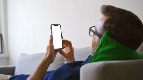 Man at home lying on sofa using smartphone with visible blank screen Stock Footage 127122770