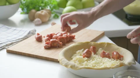 A man at home makes a deep dish pizza with cheese and sausages Stock Footage 220188032