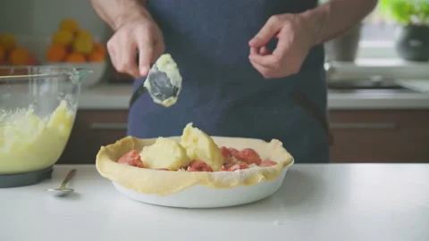 A man at home makes a pie with potatoes, cheese and sausages. Video stock 219676124