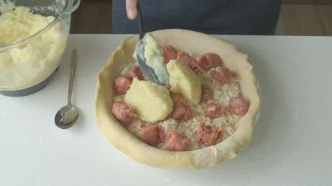 A man at home makes a pie with potatoes, cheese and sausages. Stock Footage 220188176