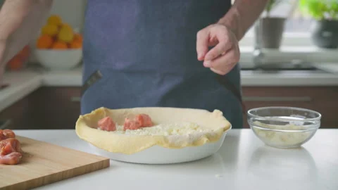 A man at home makes a pie with potatoes, cheese and sausages. Video stock 220190481