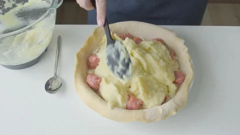 A man at home makes a pie with potatoes, cheese and sausages.. Stock Footage 221470034
