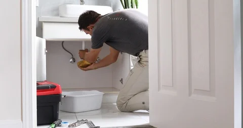 Man At Home Mopping Up Water From Leaking Pipe in Bathroom Stock Footage 120670664