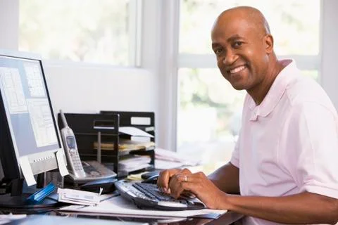 Man in home office using computer and smiling Stock Photos