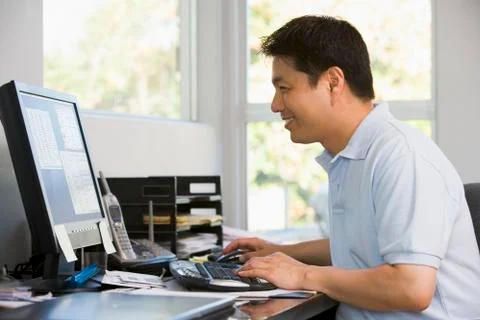 Man in home office using computer and smiling Stock Photos