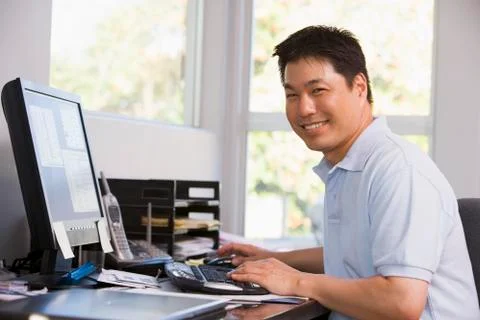 Man in home office using computer and smiling Stock Photos