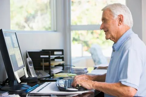 Man in home office using computer smiling Stock Photos