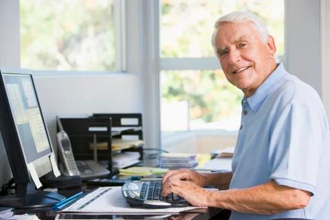 Man in home office using computer smiling Stock Photos