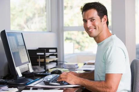 Man in home office using computer and smiling Stock Photos