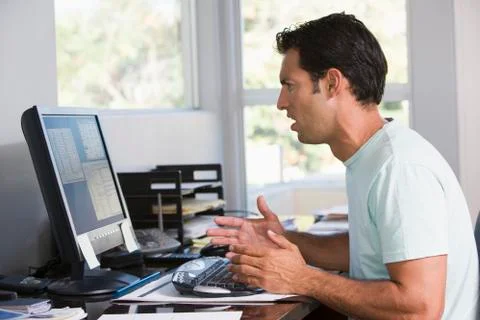 Man in home office using computer looking frustrated Stock Photos
