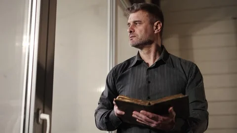 Man at home, prayer reading old literature. Man in black shirt holding Stock Footage 263080067